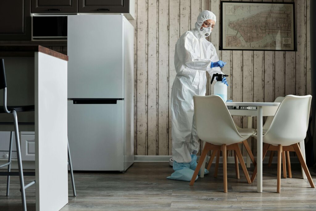 Pest control technician spraying treatment in office pantry