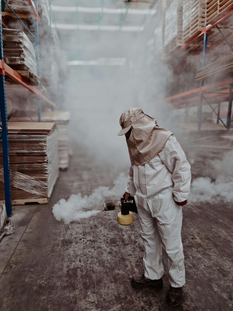 Pest control worker fumigating warehouse with protective suit and equipment